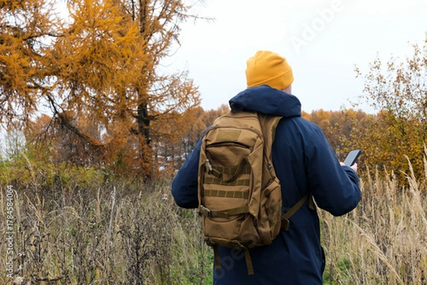 Fototapeta Hiker man navigating with phone in autumn nature
