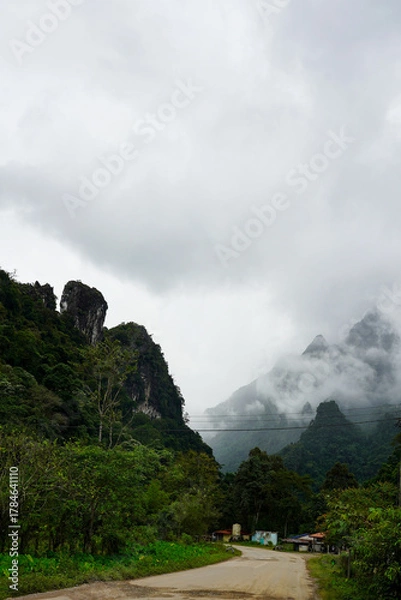 Fototapeta Small rural village surrounded by misty limestone mountains and jungle, Vang Vieng, Laos