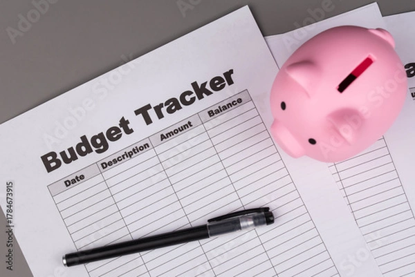 Fototapeta Open daily planner notebook on desk, with organized Monthly Budget tracking table and Piggy bank. With dates, categories and expenses. Personal finance management, spending and budgeting habits concep