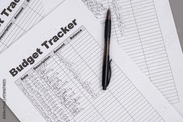 Fototapeta Open daily planner notebook on desk, with neatly handwritten organized Monthly Budget tracking table. With dates, categories and expenses. Personal finance management, spending and budgeting habits 