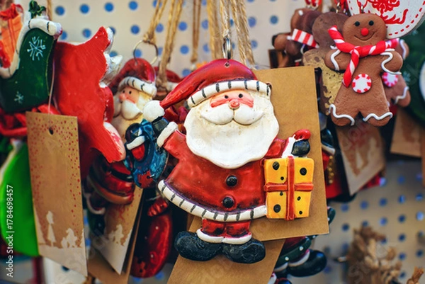 Obraz Close-up of festive Christmas keychain decorations featuring a cheerful Santa Claus with a gift and other holiday elements.