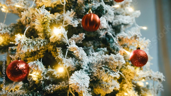 Fototapeta Christmas tree with snow-covered branches, red balls and flashing lights