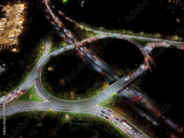 Fototapeta Aerial view over road traffic. Highway and overpass with cars and trucks, interchange, two-level road junction. Top view. Night shooting.