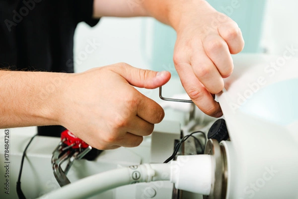 Fototapeta Technician performing detailed repair on x-ray machine component during maintenance in medical diagnostic lab.