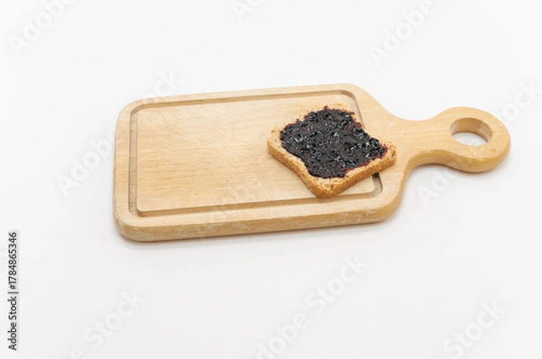 Fototapeta Feeta biscottata con confettura di mirtilli su un tagliere in legno, primo piano su fondo bianco