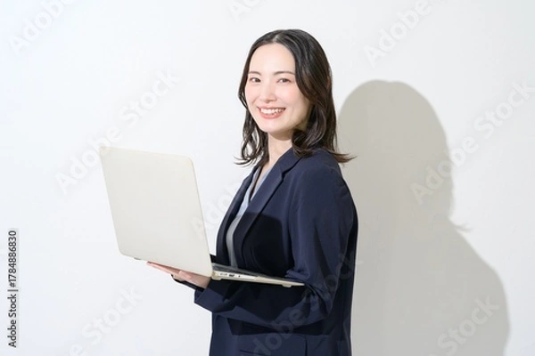 Obraz 白背景でパソコンを持つカメラ目線の日本人女性