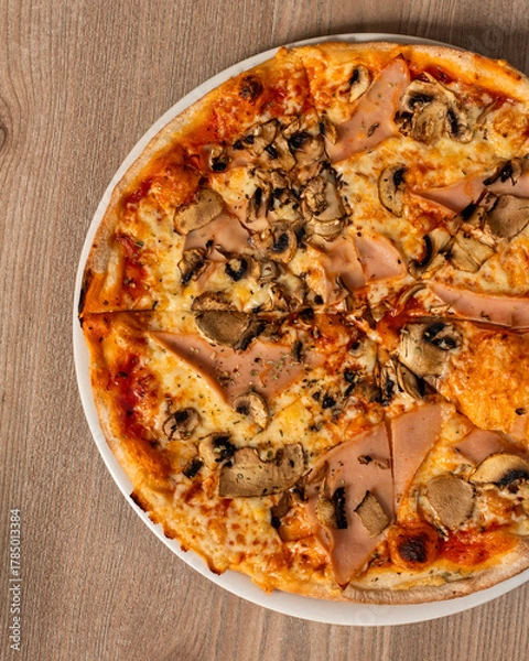 Obraz A top view of Pizza capricciosa with tomatoes, greens, mushrooms and cheese on a wooden table