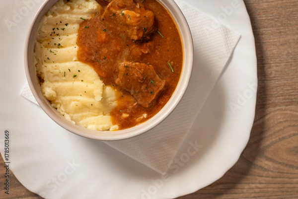 Obraz Goulash with beef and carrots with mashed potatoes top view on wooden table