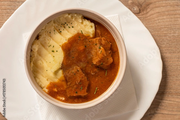Obraz Goulash with beef and carrots with mashed potatoes top view on wooden table
