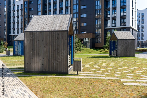 Obraz Modern wooden playhouses in urban park setting, sunny day, ideal for children's activities and community spaces, copy space

