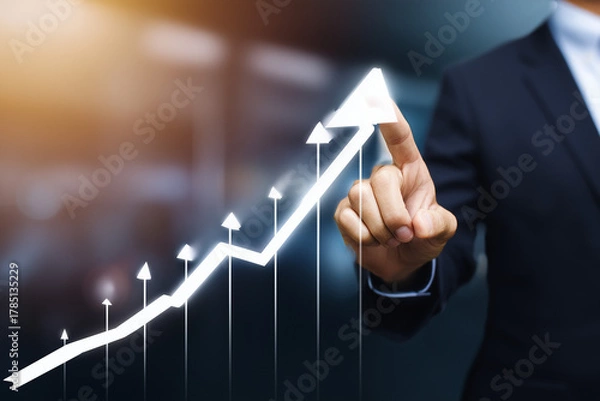 Fototapeta Businessperson pointing at a glowing upward arrow graph symbolizing growth and success.