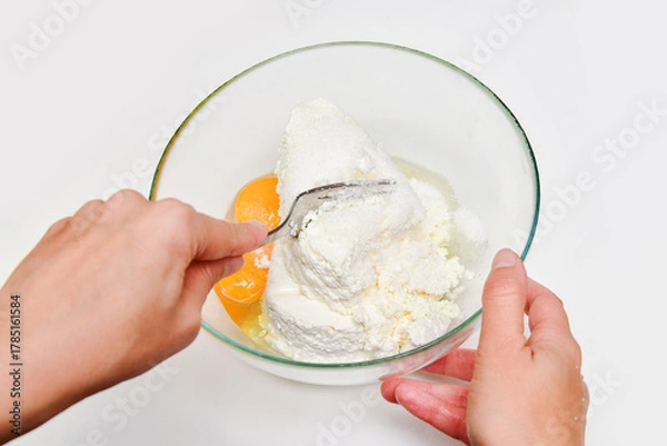 Fototapeta Woman preparing breakfast cheesecakes, mixing fresh cottage cheese with eggs