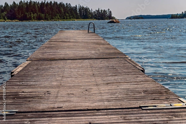 Fototapeta Wooden pier extending into tranquil Axmar bay