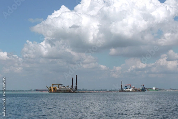 Fototapeta Heavy dredging machinery ships digging in the middle of an ocean