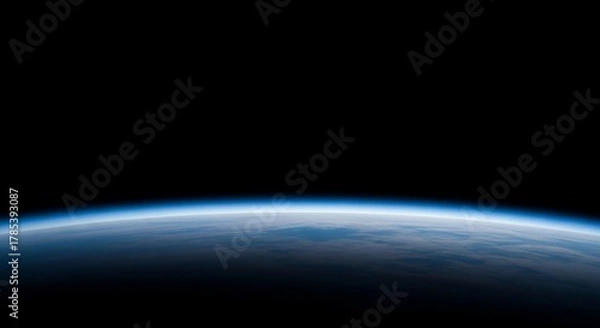 Fototapeta Earth's horizon glows with a soft blue atmospheric haze against the blackness of space, showcasing the planet's curvature.