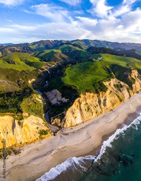 Fototapeta Aerial view of a beach, cliffs, rolling green hills under a blue sky