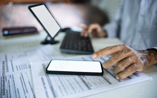Fototapeta close up shot, asian businessman work at home using mobile phone, laptop connecting to customer, checking documents before making business contract