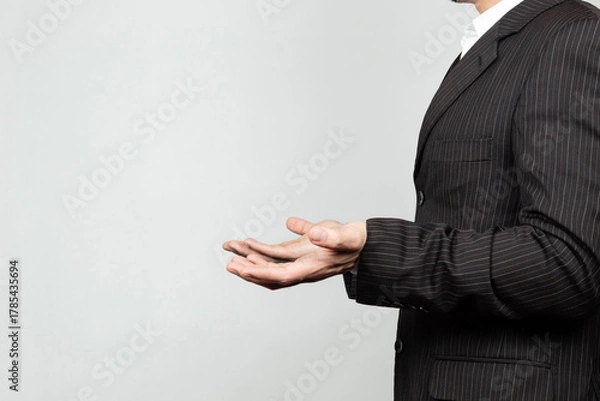 Fototapeta a businessman on suit at the right side of the screen doing a confused expression with his hands and a white background