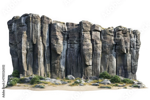 Fototapeta Tall grey columnar rock formations with green vegetation on sandy ground cliff mountain