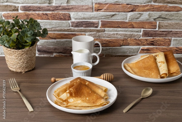 Obraz Delicious golden crepes served with honey and sauce on a rustic wooden table in a cozy setting