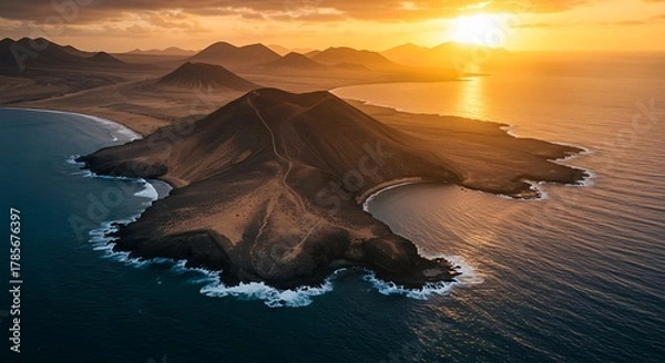 Fototapeta Aerial view of volcanic island, coastlines, and ocean during a vibrant sunset