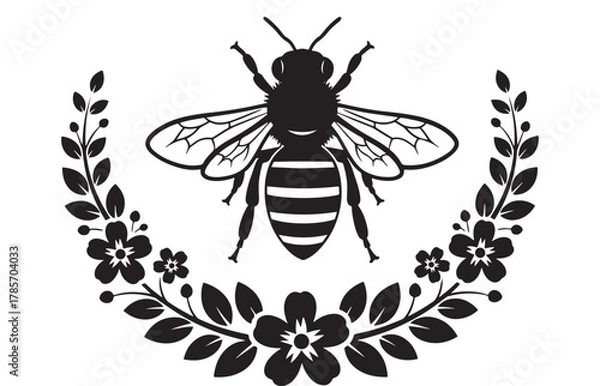 Fototapeta Black silhouette of a bee with wings spread, framed by a floral wreath, isolated on white background