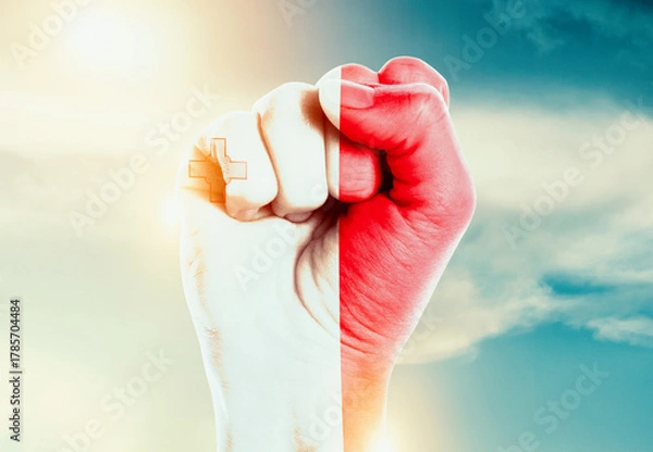 Fototapeta Malta national flag fist raise in the sky. The hand with flag raise in beautiful soft sky. Malta national flag for independence day.