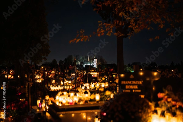Fototapeta Night scene of a cemetery illuminated by hundreds of candles during All Saints Day. Warm glowing lights, bokeh and flowers creating a peaceful, spiritual atmosphere. Shot in Biały Kościół, Poland.