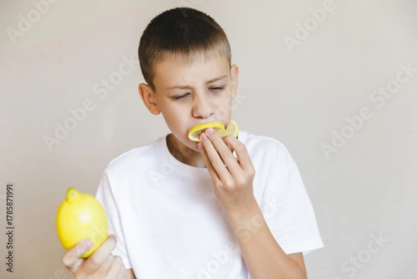 Fototapeta Boy eating fresh lemon isolated on white background. Citrus.portrait boy with lemon.