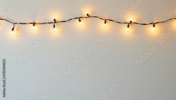 Obraz String of warm glowing patio lights draped horizontally against a plain light background