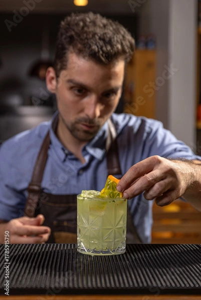 Fototapeta Bartender garnishing a cocktail with kiwano