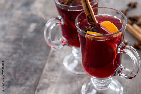 Obraz Mulled Wine with Orange and Cinnamon Sticks and Christmas decoration on wooden table. Copy space