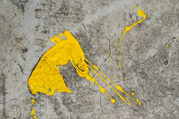 Fototapeta A dynamic splatter of bright yellow paint contrasts sharply against a cracked and textured grey concrete surface