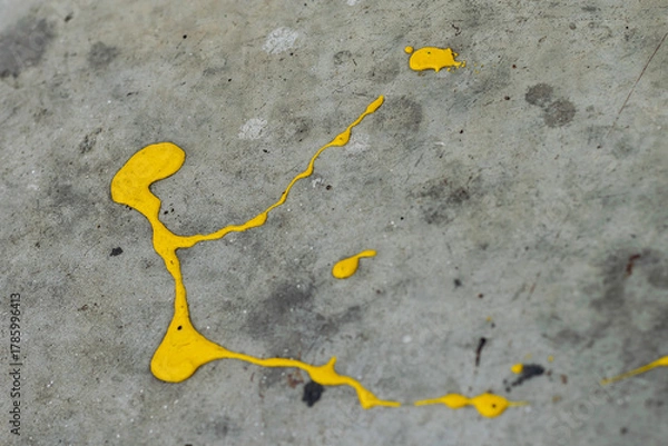 Fototapeta A dynamic splatter of bright yellow paint contrasts sharply against a cracked and textured grey concrete surface