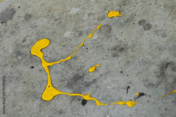 Fototapeta A dynamic splatter of bright yellow paint contrasts sharply against a cracked and textured grey concrete surface
