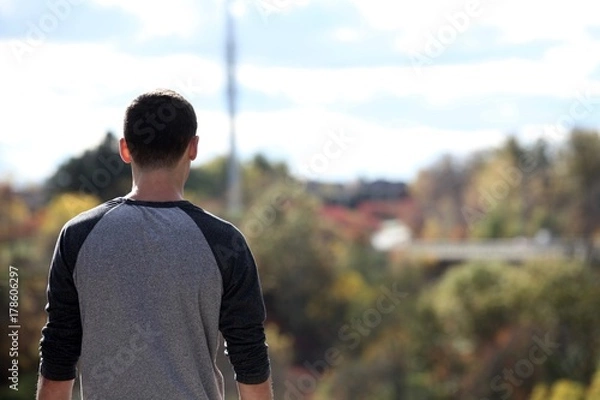 Fototapeta Teenage boy overlooking a view from the top of a mountain