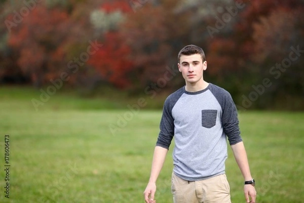 Fototapeta Portrait of a teenage boy posing with a serious face outdoors