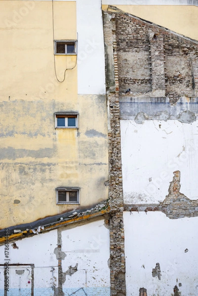Fototapeta A partially destroyed wall reveals old bricks and textures showing the decay and history of an abandoned urban building.