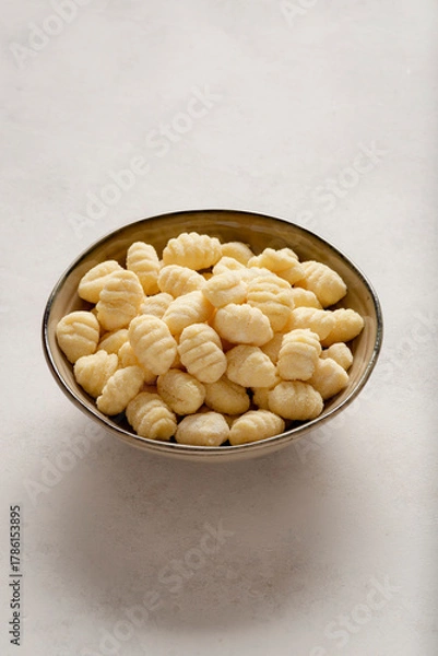 Obraz A bowl filled with raw gnocchi placed against a light background