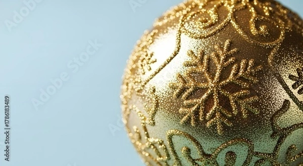 Fototapeta Close-up of a shimmering golden Christmas ornament with intricate snowflake patterns, perfect for festive holiday season decorations