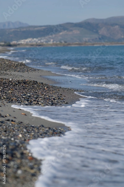 Obraz Pebble beach with gentle sea waves and mountains in the background