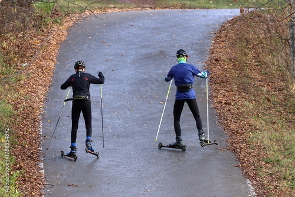 Fototapeta Roller skaters climb a hill on a track in the park