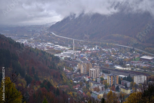 Fototapeta remote mountain village nestled in valley with foggy peaks and vibrant autumn colors