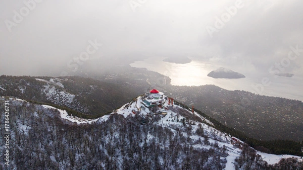 Obraz Aerial view of Cerro Otto snowy summit and panoramic lake with clouds and islands in Bariloche, Argentina.