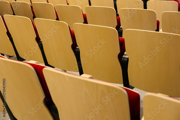 Fototapeta Empty auditorium seats in staggered rows waiting for audience