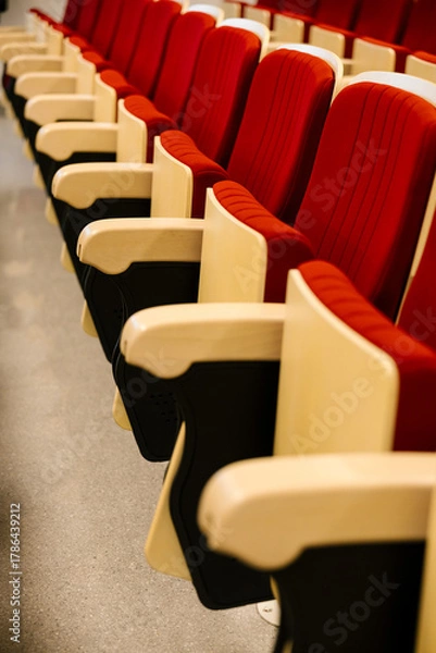Fototapeta Empty auditorium hall with red chairs and beige armrests