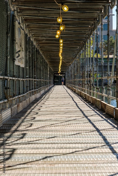 Obraz Protective scaffolding for pedestrians with lighting along a river in Indianapolis, Indiana