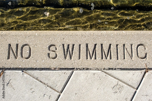 Obraz No swimming text warning stamped in cement beside water