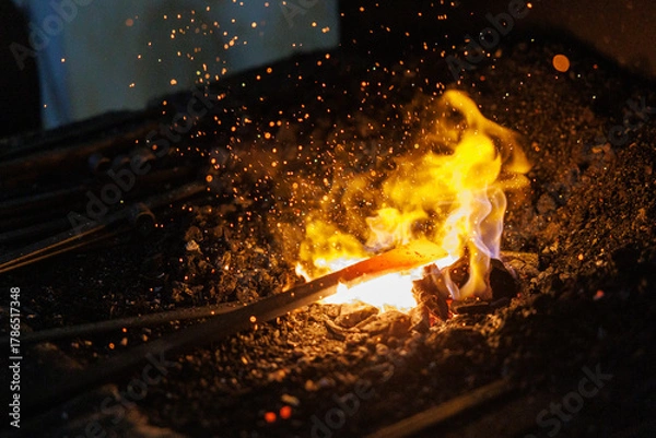 Obraz Blacksmith heating metal in hot forge creating sparks