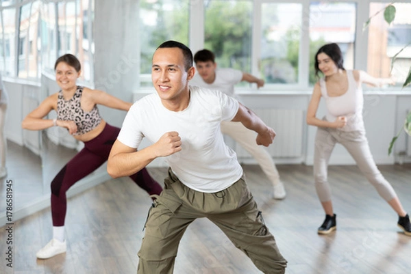 Fototapeta Smiling people practicing vigorous lindy hop movements in dance class